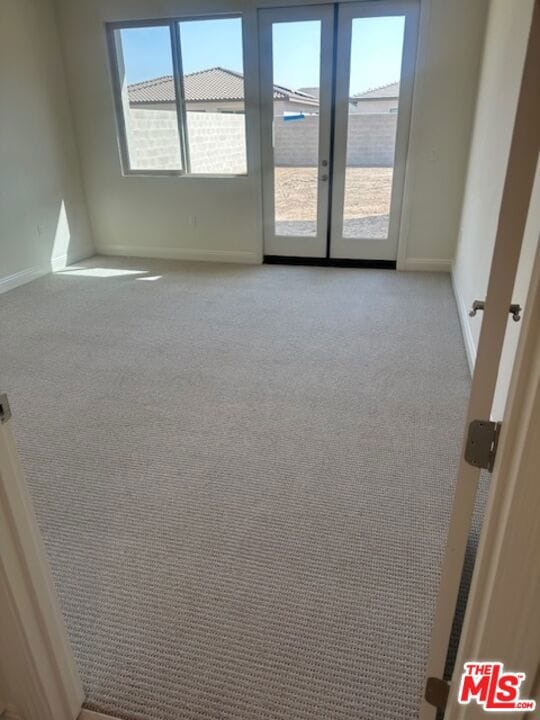 empty room featuring french doors and light colored carpet