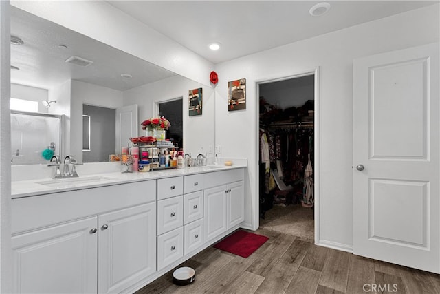 bathroom featuring wood-type flooring, a shower with shower door, and vanity