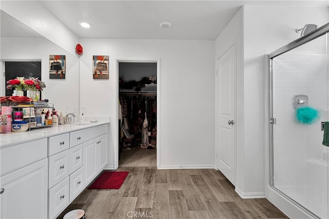 bathroom featuring wood-type flooring, a shower with shower door, and vanity