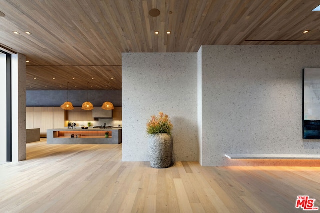 additional living space with wood ceiling, light hardwood / wood-style flooring, and sink