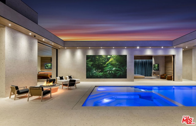 pool at dusk featuring an outdoor hangout area, an in ground hot tub, and a patio