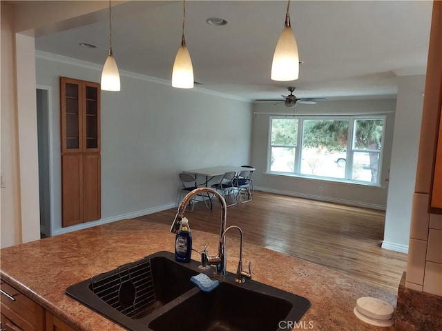 kitchen featuring pendant lighting, light hardwood / wood-style floors, ornamental molding, and sink