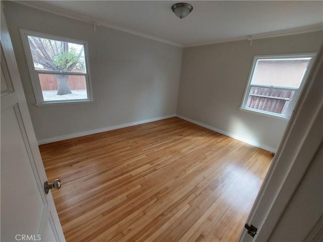 empty room featuring light hardwood / wood-style flooring and crown molding