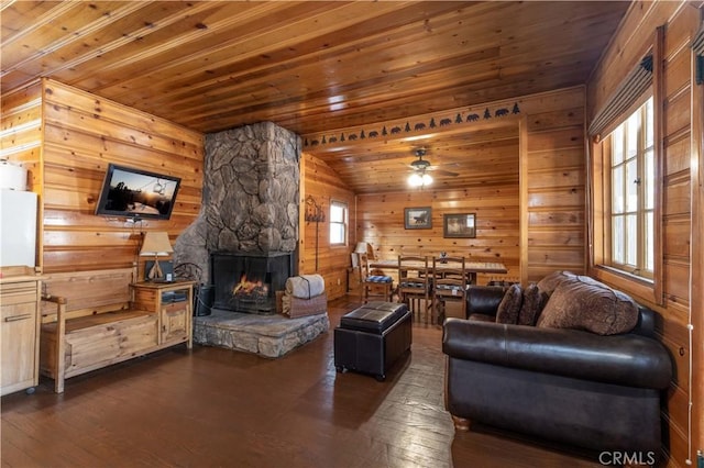 living room with wood walls, wooden ceiling, a stone fireplace, and dark hardwood / wood-style floors