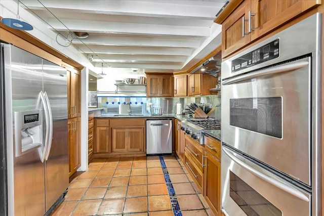 kitchen with pendant lighting, sink, light tile patterned floors, beamed ceiling, and stainless steel appliances