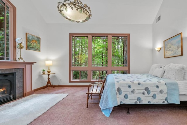 carpeted bedroom with a tiled fireplace and high vaulted ceiling