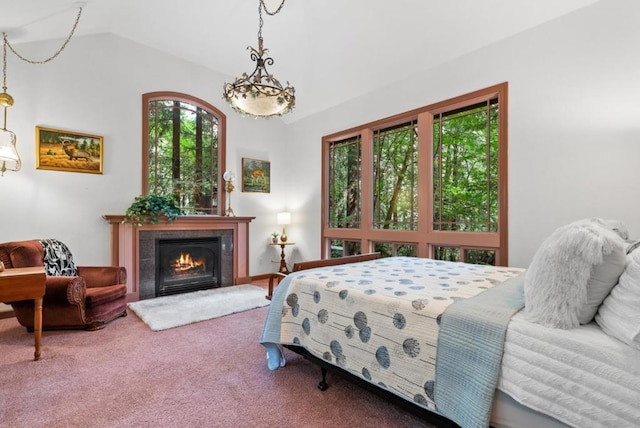 bedroom featuring vaulted ceiling, a tiled fireplace, and carpet floors