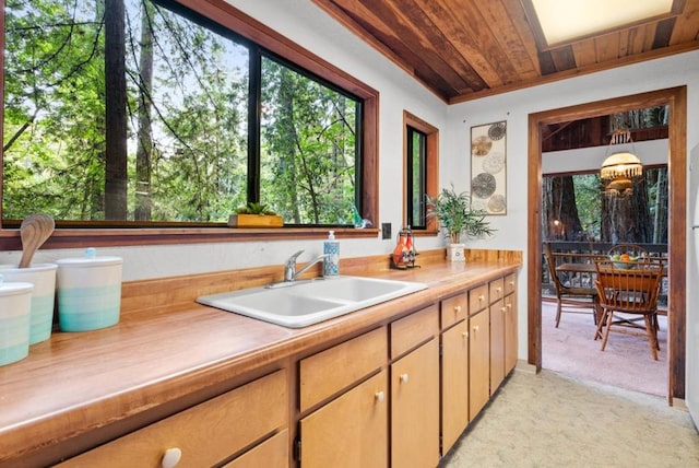 kitchen featuring a wealth of natural light, wood ceiling, light colored carpet, and sink