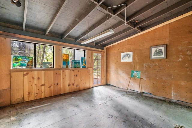 unfurnished room with lofted ceiling and wood walls