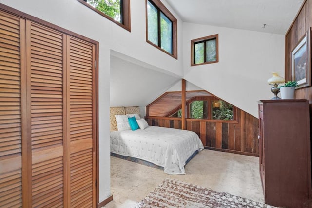 bedroom with vaulted ceiling and wood walls