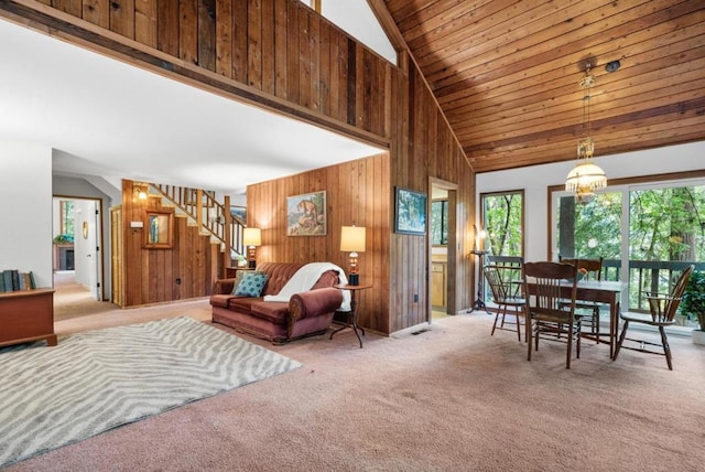 carpeted living room with high vaulted ceiling, a chandelier, wood ceiling, and wooden walls