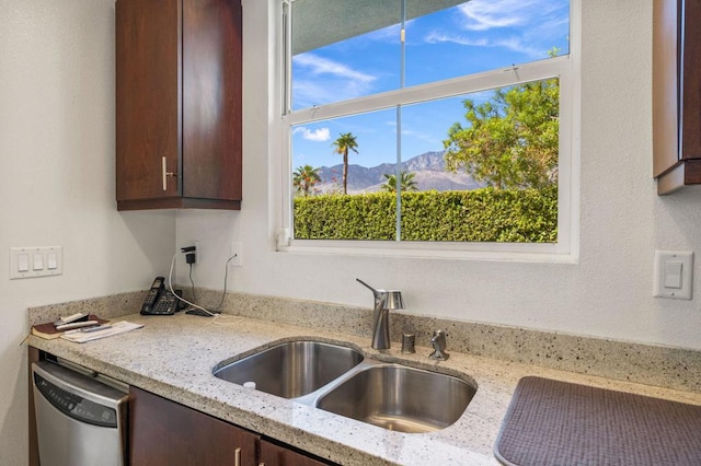 kitchen featuring a mountain view, light stone counters, stainless steel dishwasher, and sink