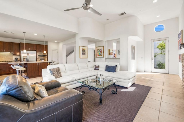 living room with ceiling fan, light tile patterned floors, and a high ceiling