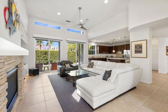 living room with ceiling fan, a fireplace, high vaulted ceiling, and light tile patterned floors