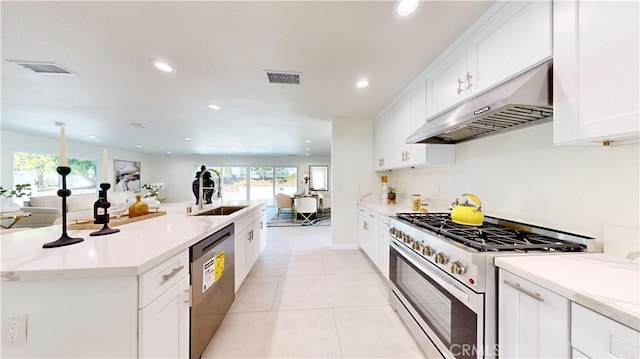 kitchen featuring appliances with stainless steel finishes, sink, light stone counters, light tile patterned flooring, and white cabinets