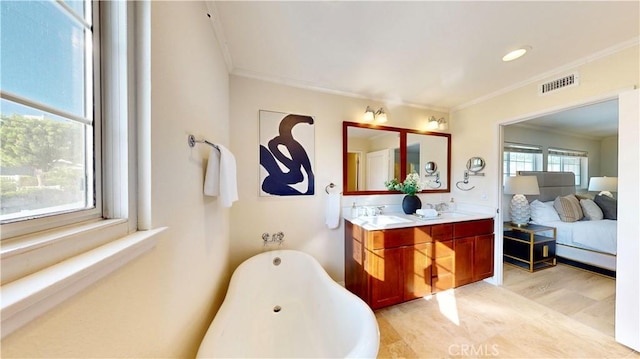 bathroom featuring a bathing tub, vanity, crown molding, and wood-type flooring