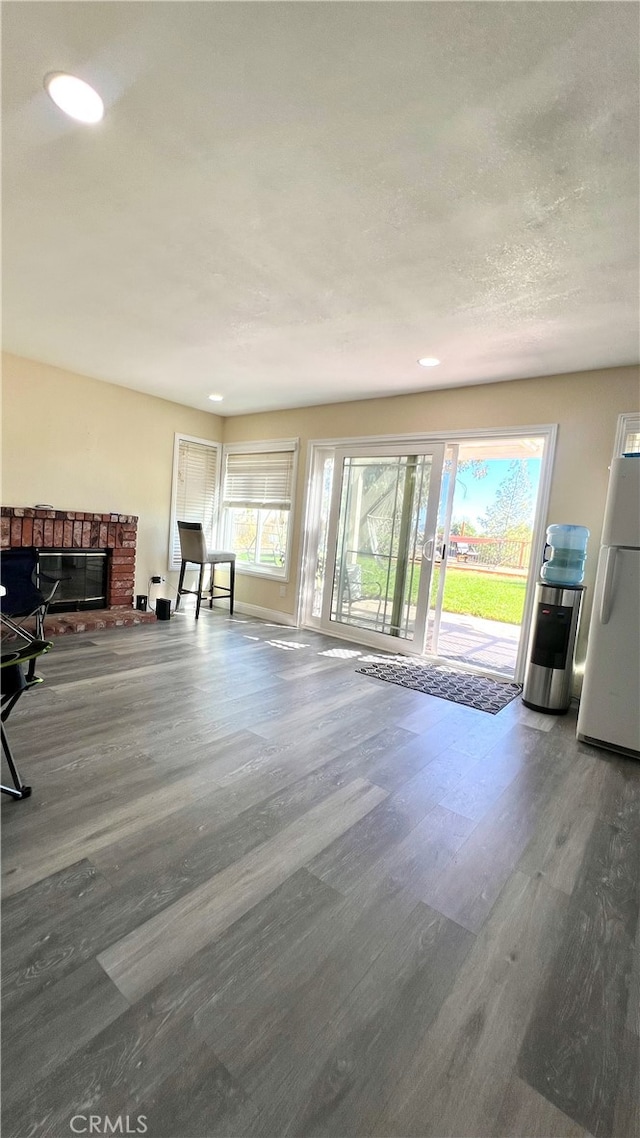 unfurnished living room with wood-type flooring and a brick fireplace