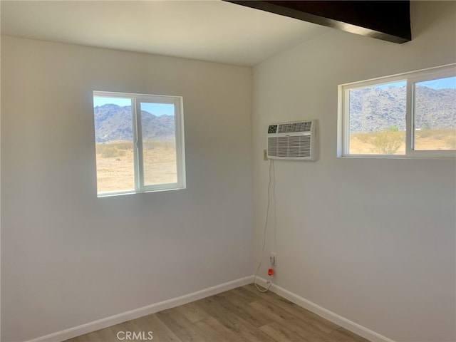 spare room featuring wood-type flooring, a wall mounted AC, and a mountain view