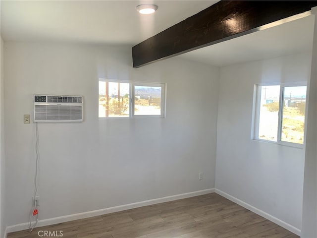 spare room with plenty of natural light, light wood-style flooring, an AC wall unit, and baseboards