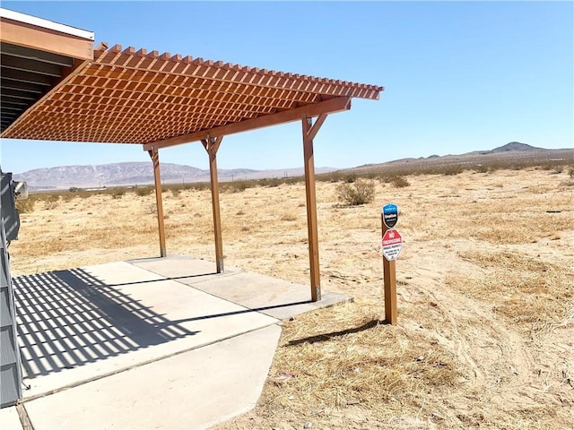 view of patio / terrace with a pergola, a mountain view, and a desert view