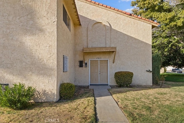 view of exterior entry featuring a lawn