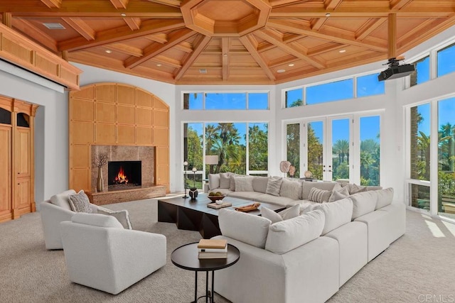 living room with light colored carpet, wood ceiling, a towering ceiling, and a fireplace