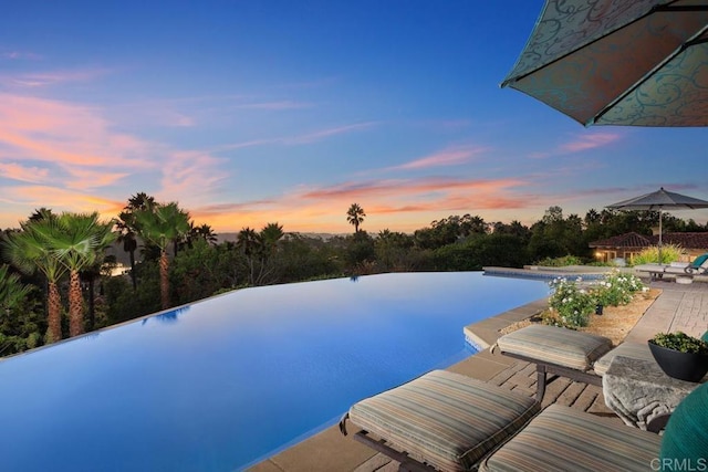 pool at dusk with a patio area