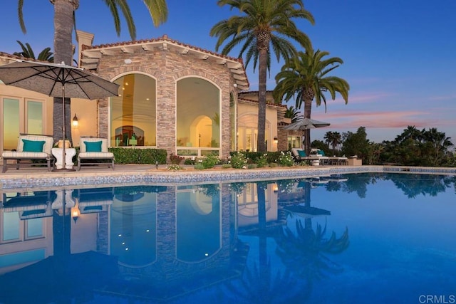 pool at dusk with a patio area