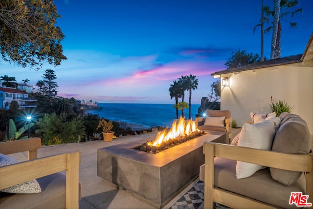 patio terrace at dusk with a water view and a fire pit