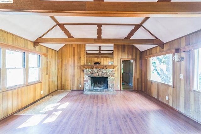 unfurnished living room featuring vaulted ceiling with beams, wood walls, and hardwood / wood-style floors