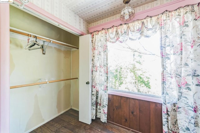 unfurnished bedroom with wooden walls, a closet, and dark hardwood / wood-style floors