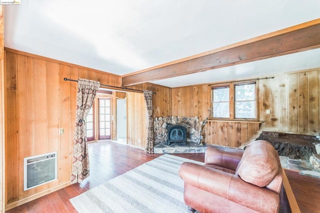 living room featuring wood-type flooring, heating unit, beam ceiling, and a healthy amount of sunlight