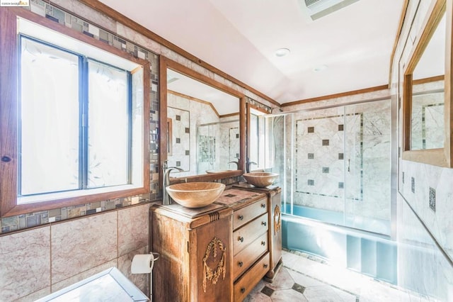 bathroom featuring ornamental molding, bath / shower combo with glass door, tile walls, and vanity