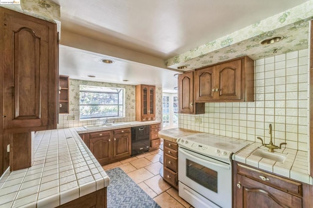 kitchen featuring dishwasher, tile counters, electric range, and tasteful backsplash