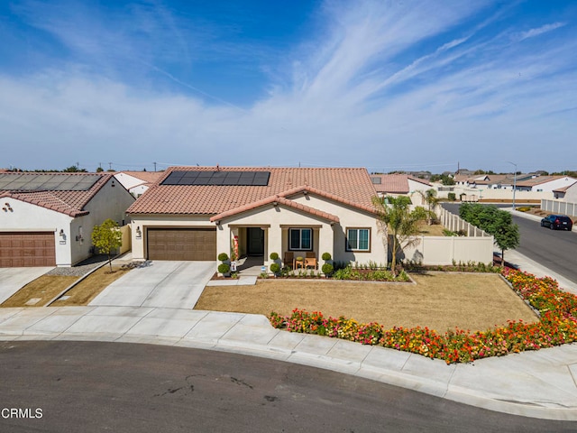 mediterranean / spanish-style house featuring a garage, solar panels, and a front lawn