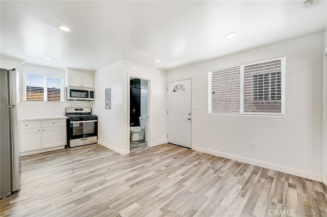 kitchen with light wood-type flooring, stainless steel appliances, and white cabinetry