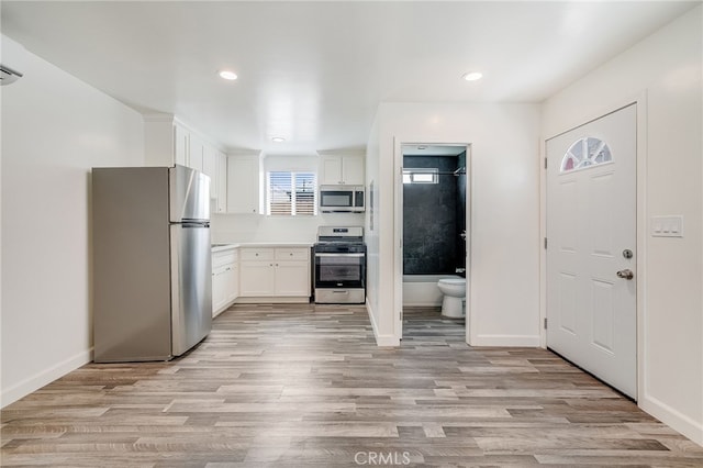 kitchen with appliances with stainless steel finishes, light hardwood / wood-style floors, and white cabinetry