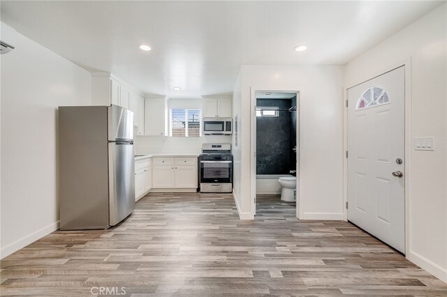916 W 88th St, Los Angeles, CA 90044 - kitchen featuring white cabinets, stainless steel appliances, baseboards, and light wood-style flooring