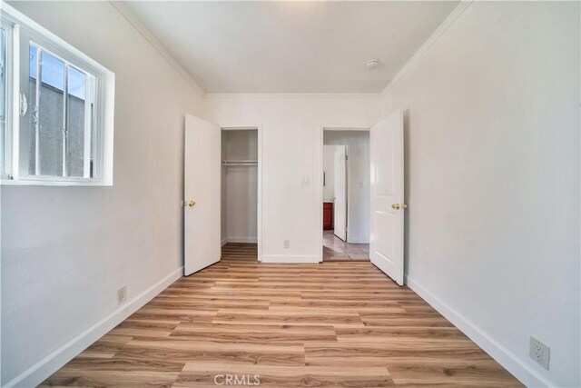 unfurnished bedroom with crown molding, a closet, and light hardwood / wood-style floors