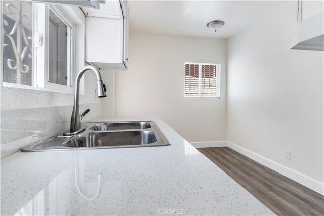 kitchen with white cabinetry, sink, dark wood-type flooring, and light stone counters