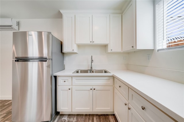 916 W 88th St, Los Angeles, CA 90044 - kitchen with white cabinets, a sink, an AC wall unit, freestanding refrigerator, and wood finished floors