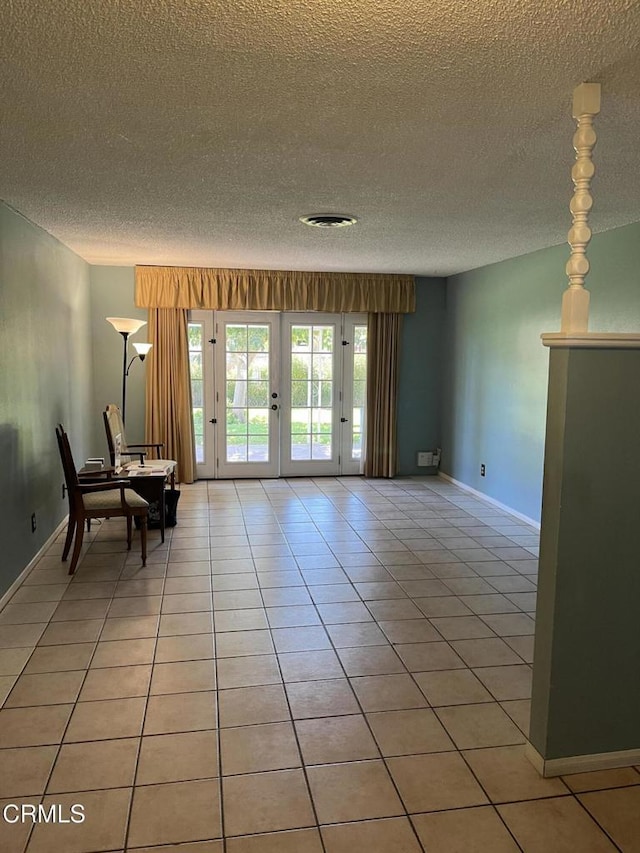 interior space featuring light tile patterned floors, a textured ceiling, and french doors