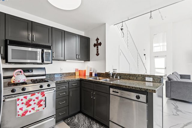 kitchen featuring kitchen peninsula, appliances with stainless steel finishes, sink, and dark stone counters