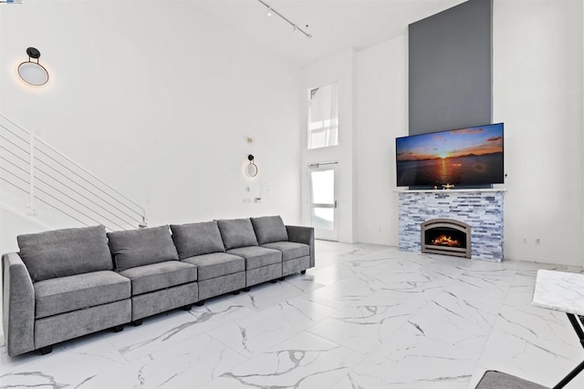 living room featuring rail lighting, a high ceiling, and a tile fireplace