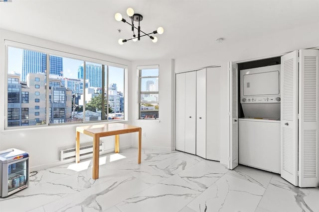 home office with an inviting chandelier, a baseboard heating unit, and stacked washer / drying machine