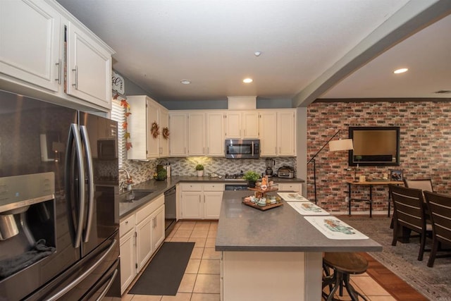 kitchen featuring light tile patterned flooring, sink, stainless steel appliances, white cabinets, and a center island