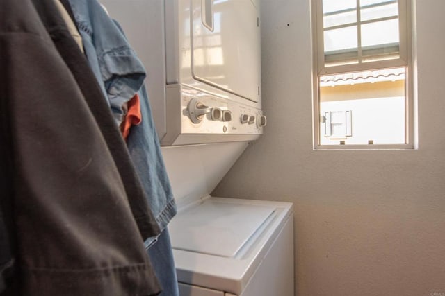 washroom featuring stacked washer and clothes dryer and a wealth of natural light