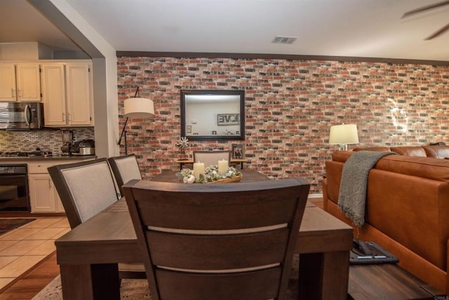 dining space featuring brick wall and light hardwood / wood-style flooring