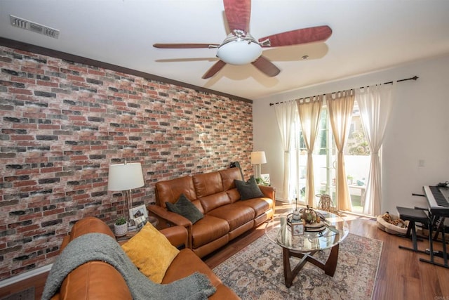 living room with brick wall, hardwood / wood-style floors, and ceiling fan