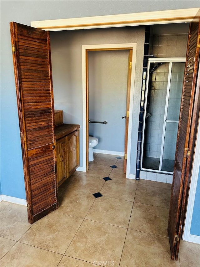 bathroom featuring tile patterned flooring, toilet, and walk in shower